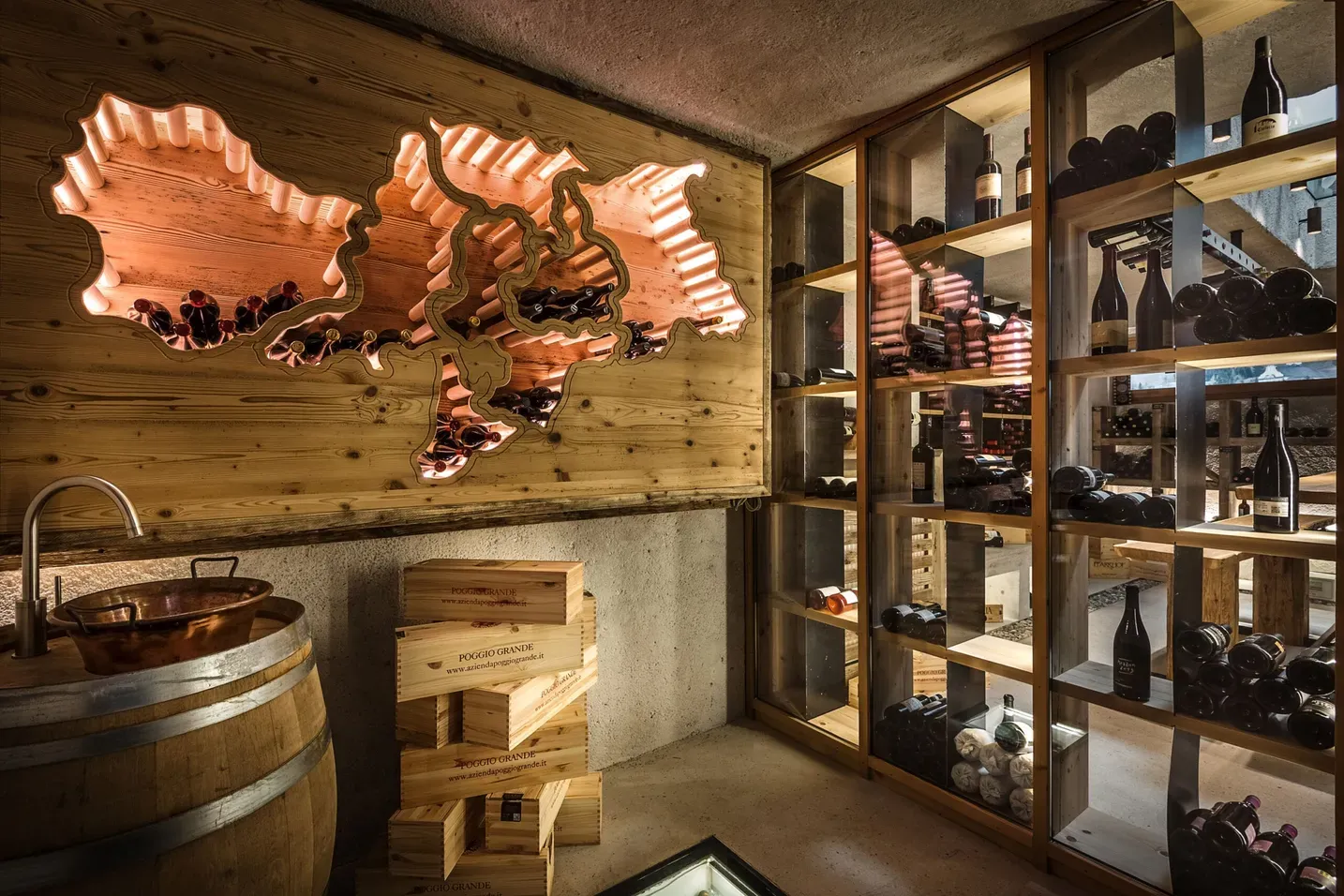 Weinlager im Hotel Gran Ander, Badia, Alta Badia, Dolomiten: warme Holzwände, Neon-Dolomitenkarte, Weinschränke, Holzkisten und eine Kupferwanne auf einem Fass.
